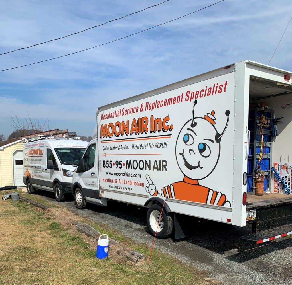 Moon Air technician servicing HVAC unit outdoors, tools and gauges attached