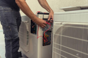 Moon Air technician servicing central AC unit at suburban home exterior
