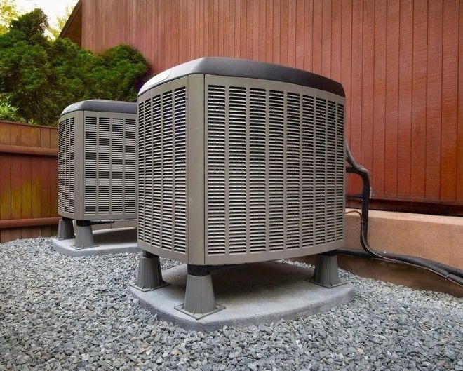 Moon Air technician servicing central AC unit at suburban home exterior