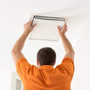 Homeowner installing a new ceiling return air filter as part of air filter service in Elkton, MD.